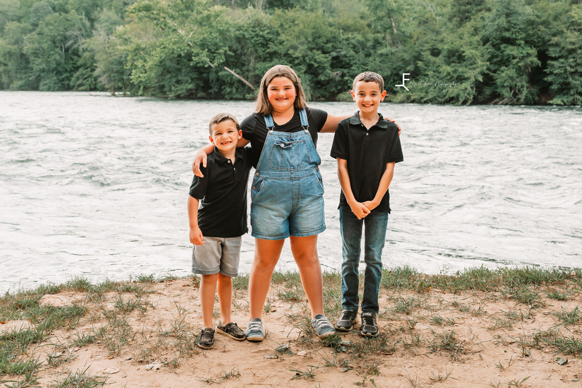 2 boys 1 girl standing on river bank 