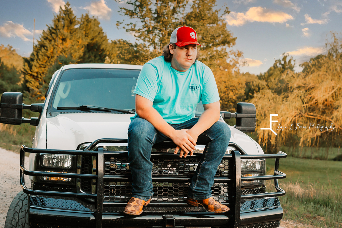 guy sitting on truck with boots and red hat