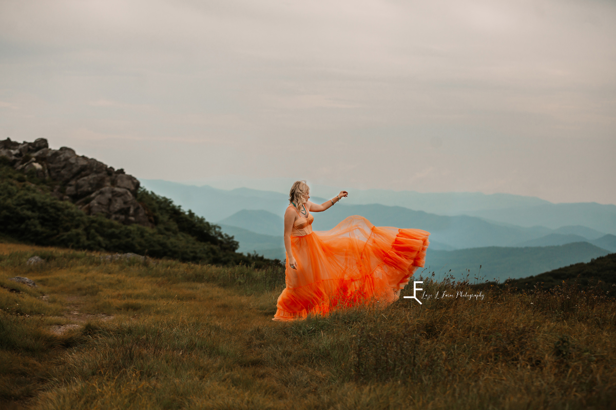 girl in orange dress with wind picking up skirt