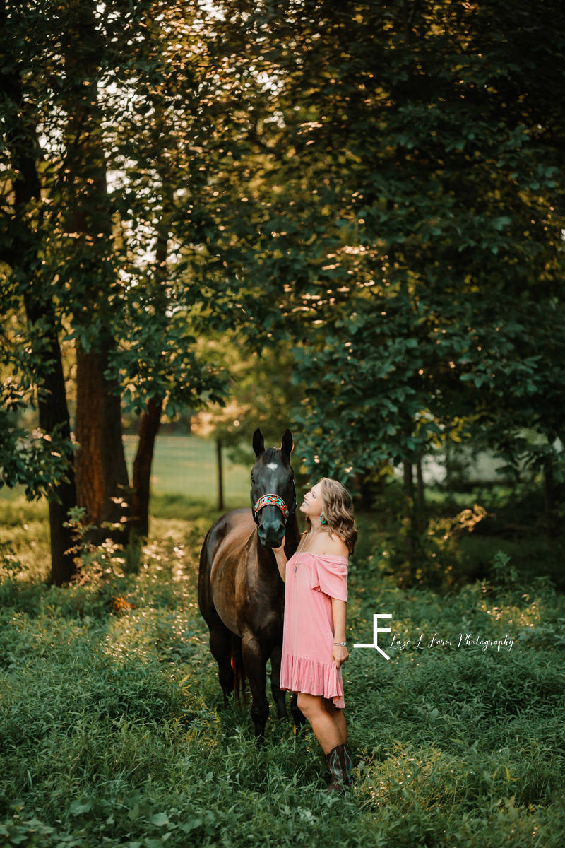 girl in pink dress looking at horse 