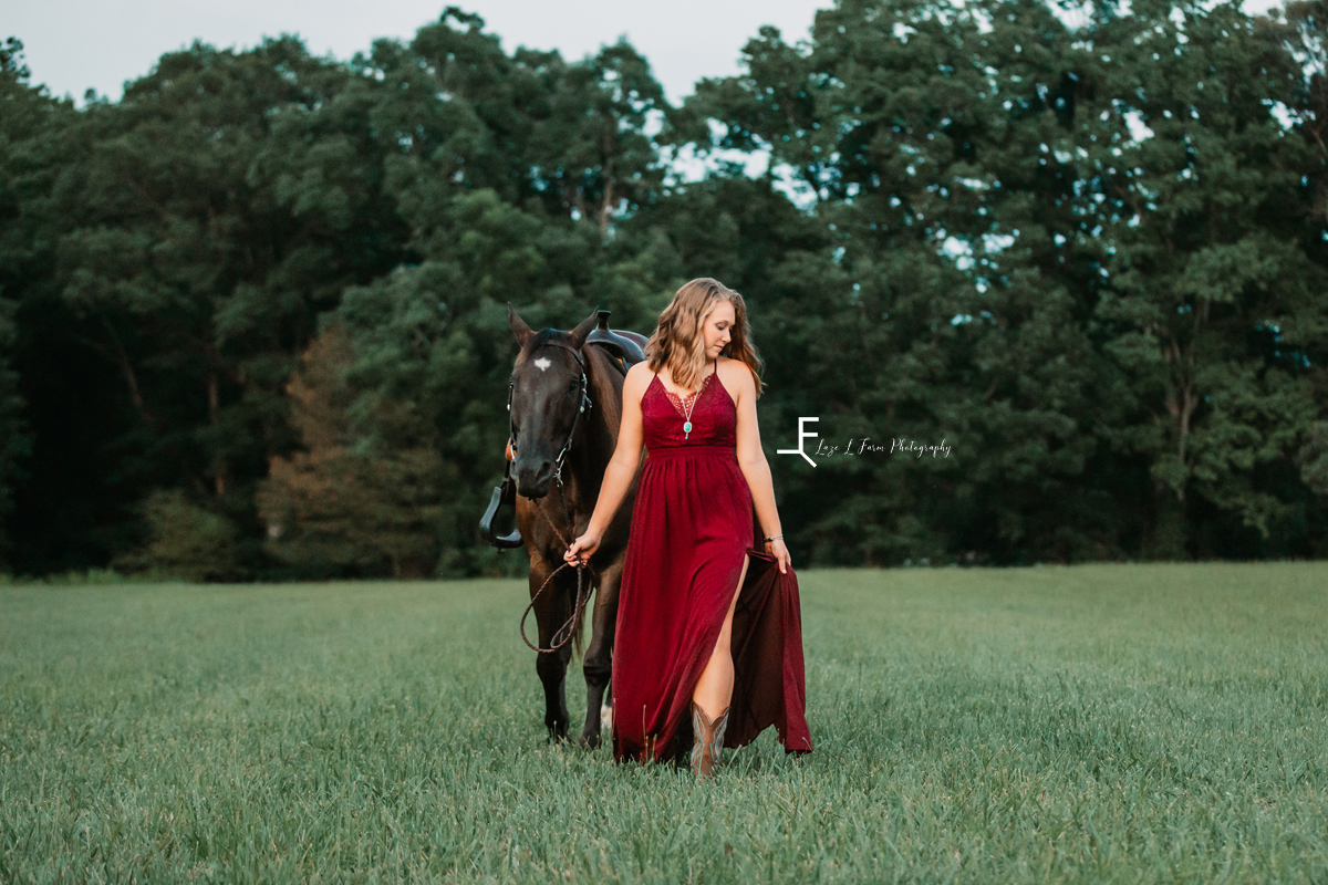 girl in red dress walking horse