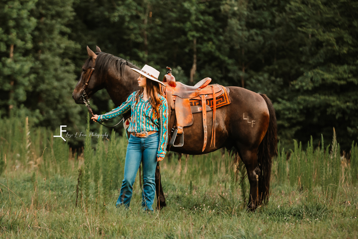 girl standing with black horse looking left