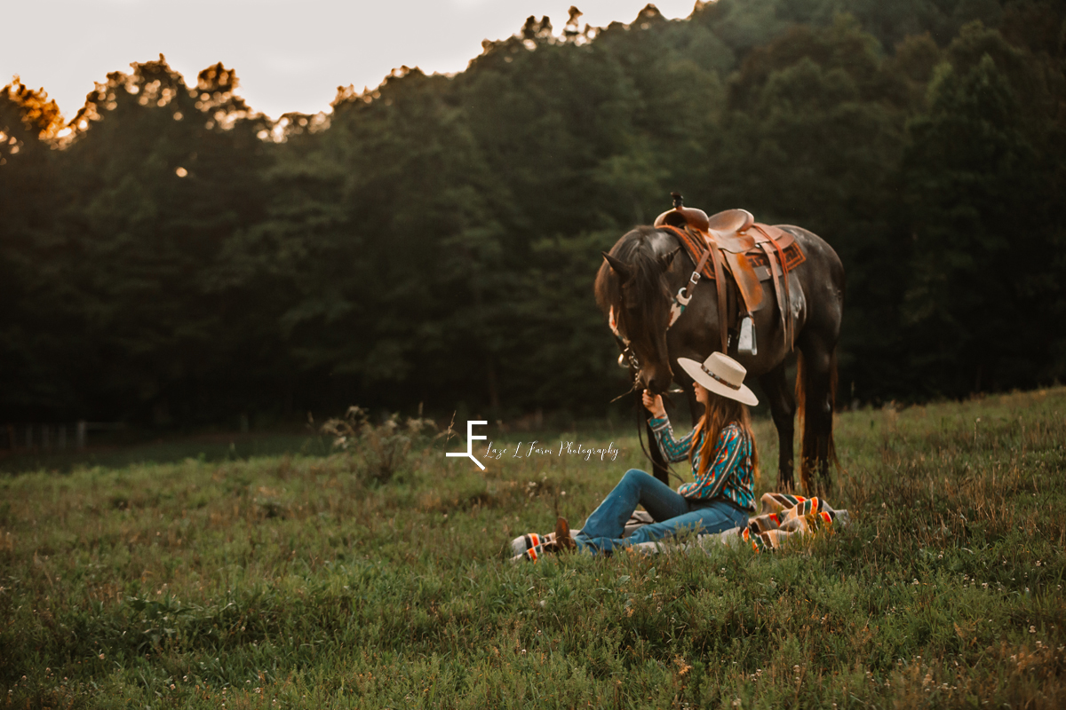 girl sitting in field with black horse
