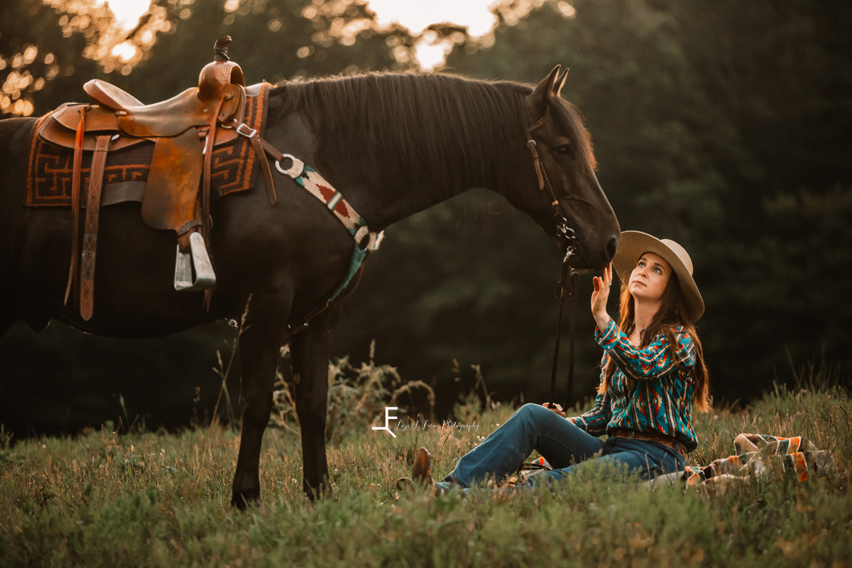 girl sitting with black horse petting him