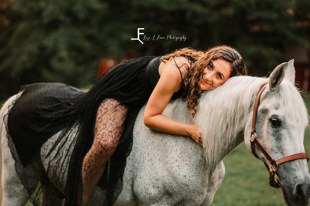 girl in black dress on horse hugging horse's neck