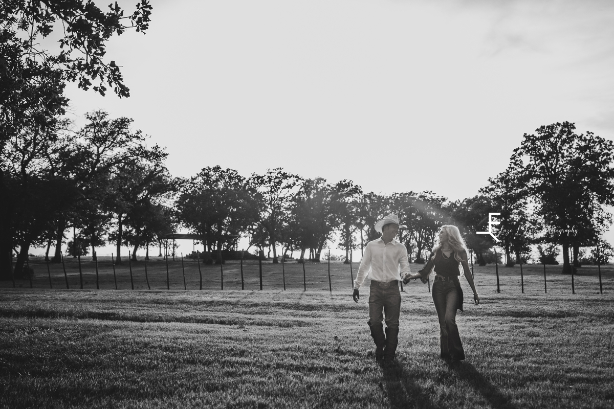 man and woman walking in field in black and white