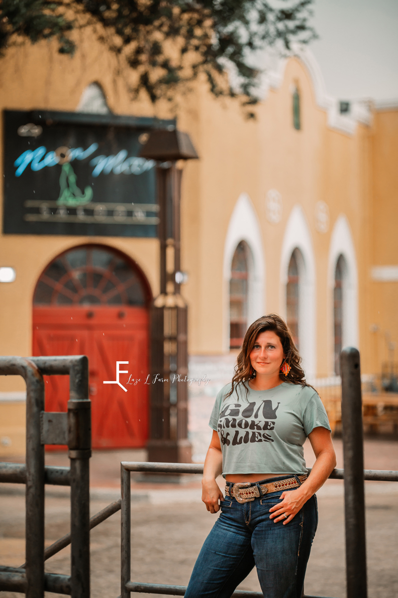 girl in gunsmoke and lies tee in front of building