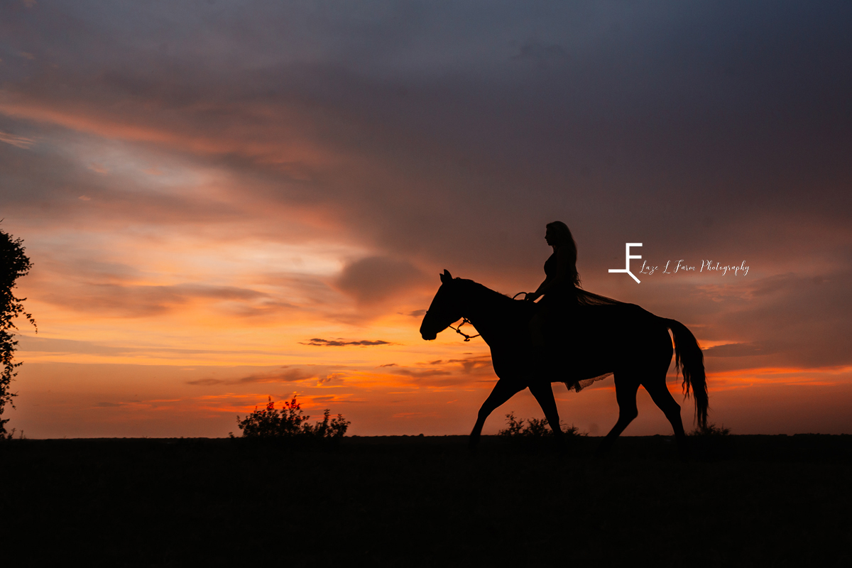 woman in dress riding horse in front of sunset