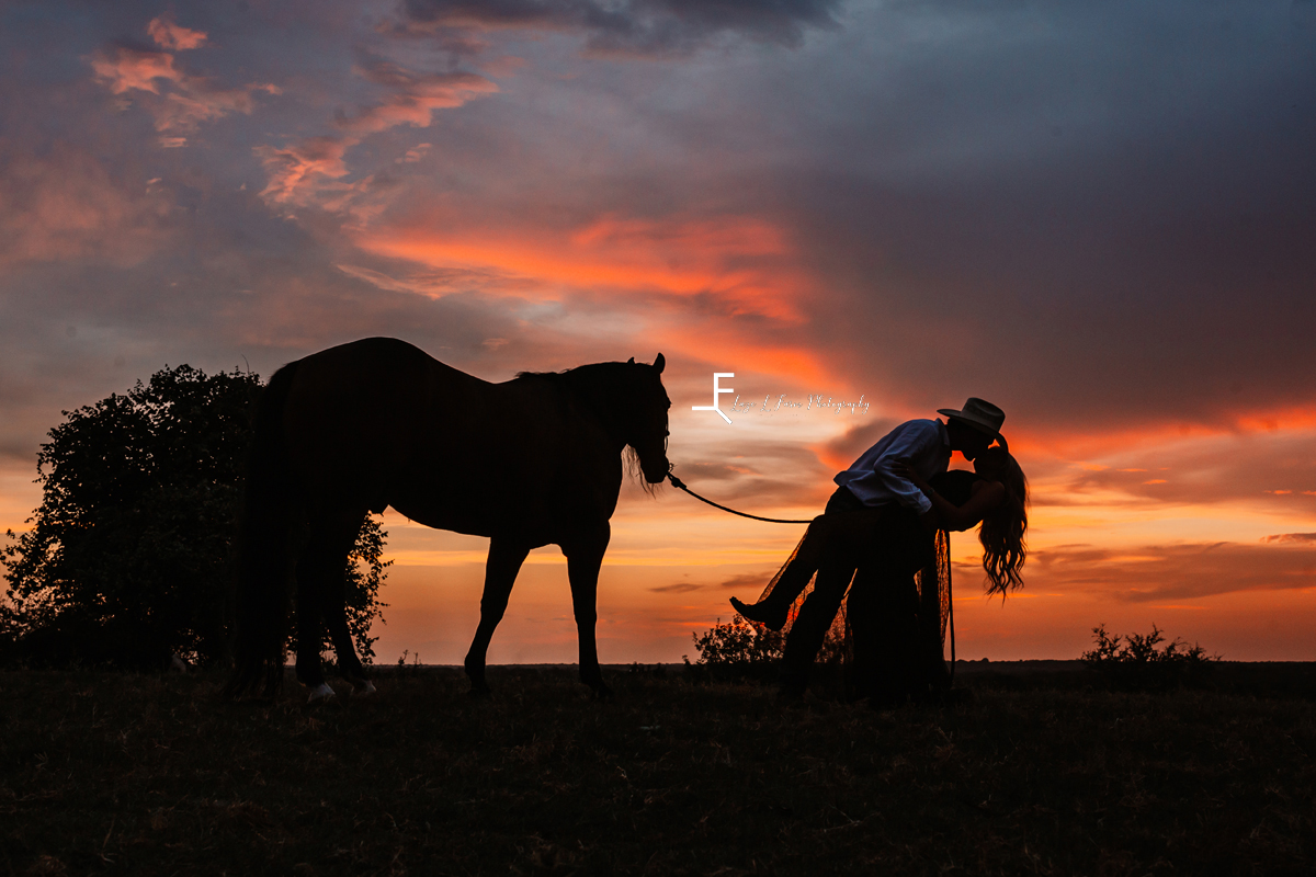 cowboy dipping wife with horse in front of sunset