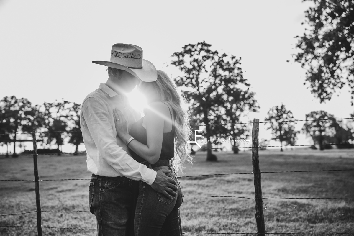 cowboy hugging wife with sun behind them in black and white