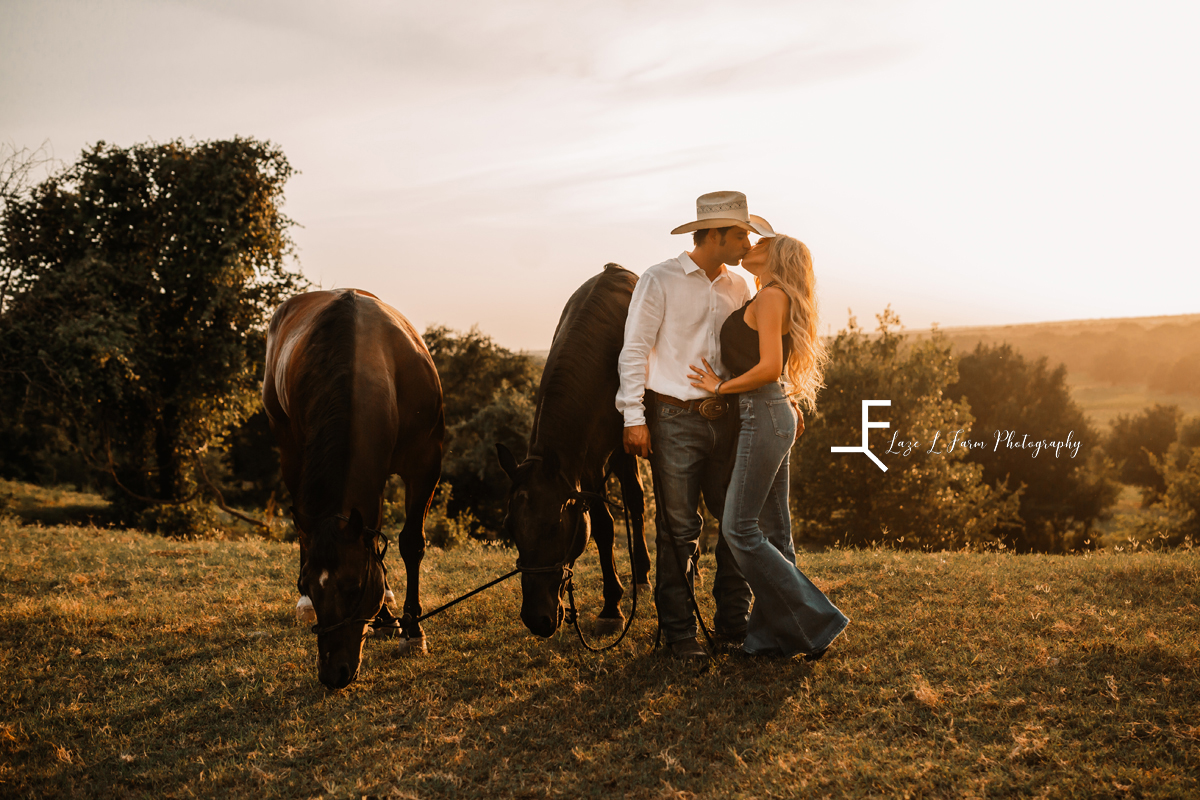 cowboy and wife kissing with 2 horses beside them