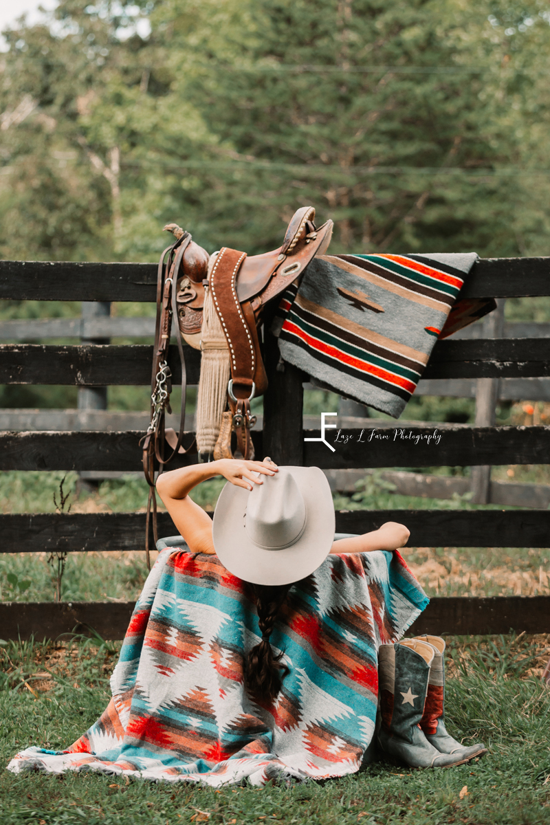 cowgirl with black braid holding hat in water trough