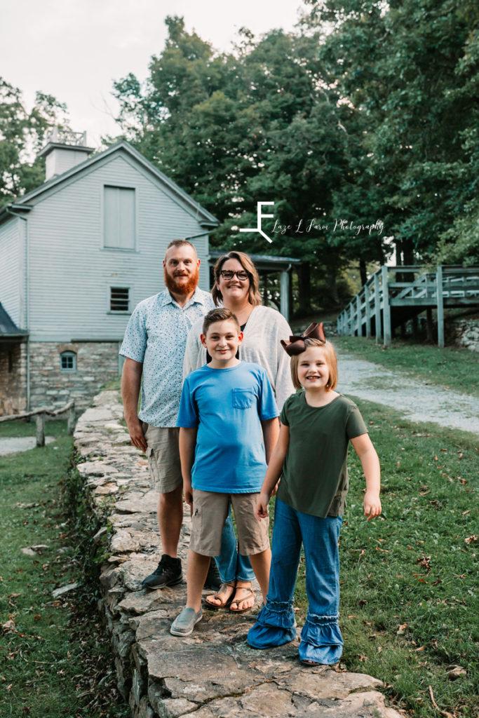 mom dad and 2 kids in front of old house