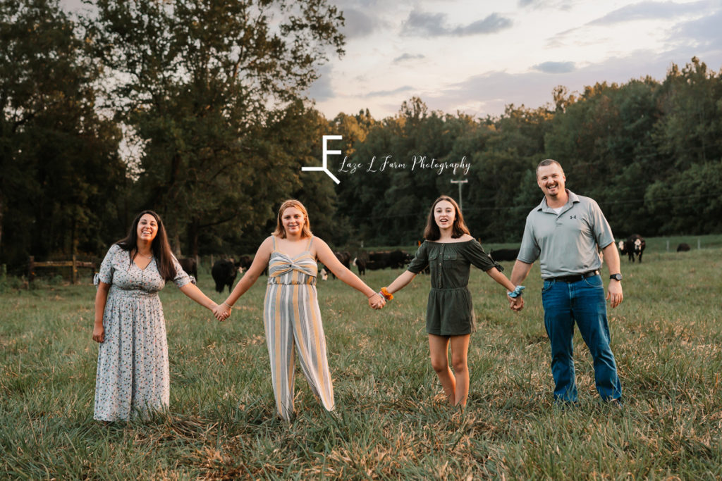 family walking in a field holding hands