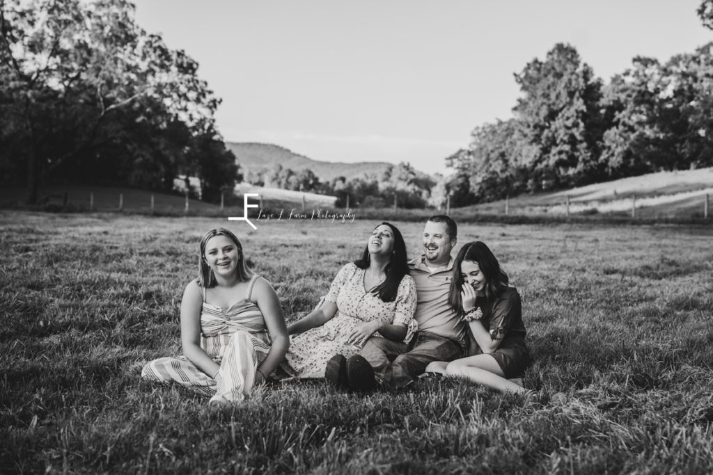 family sitting in field in black and white