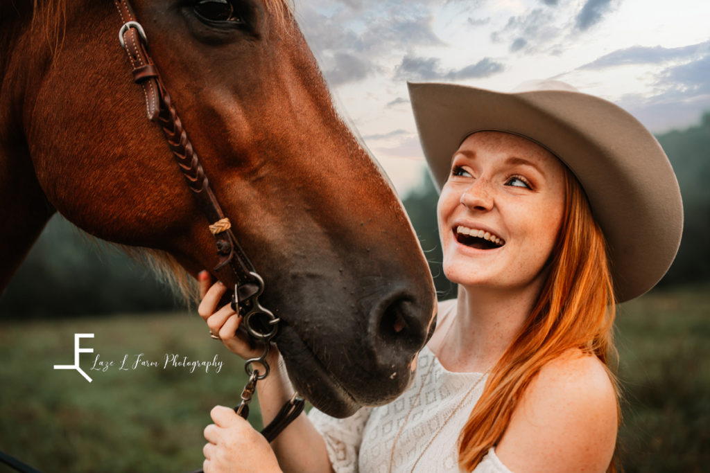 red haired cowgirl with horse laughing