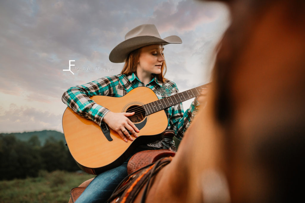 cowgirl playing guitar on horseback