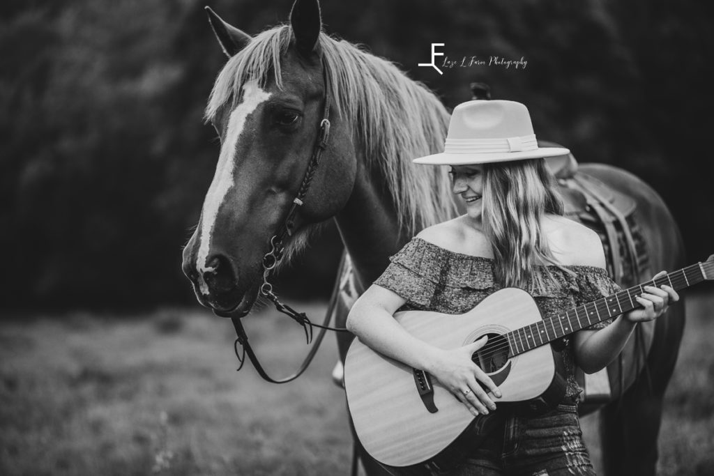 girl playing guitar with horse in black and white