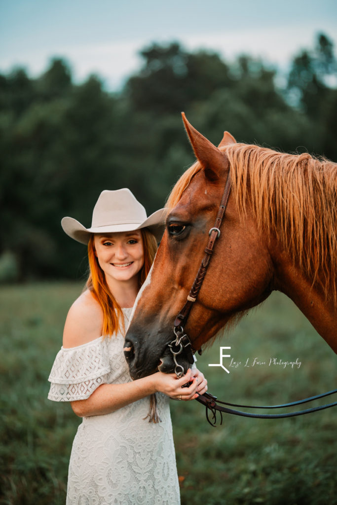 redhair cowgirl in white dress smiling with horse