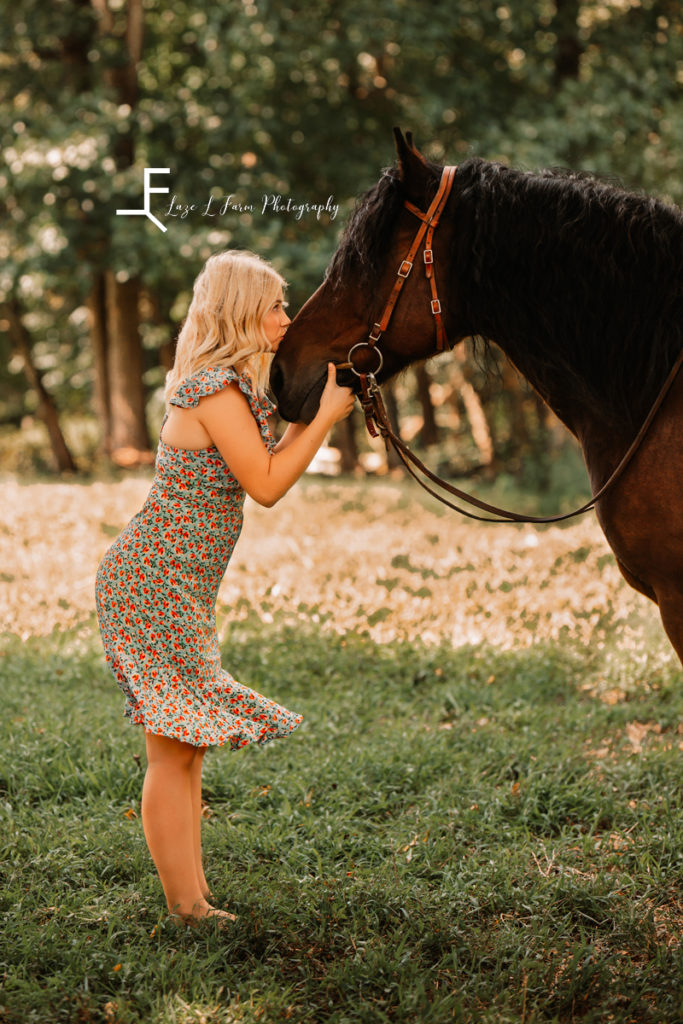 blonde girl wearing a knee length dress kissing horse