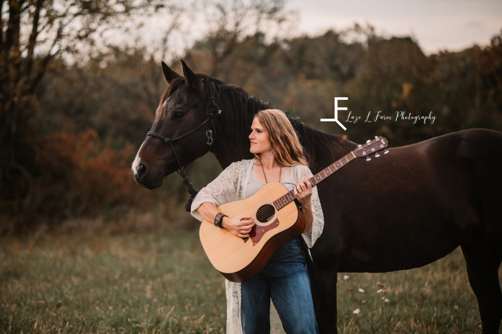 girl with horse and guitar looking off to the left