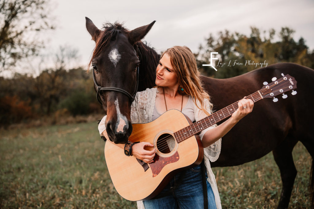 girl with guitar looking at horse