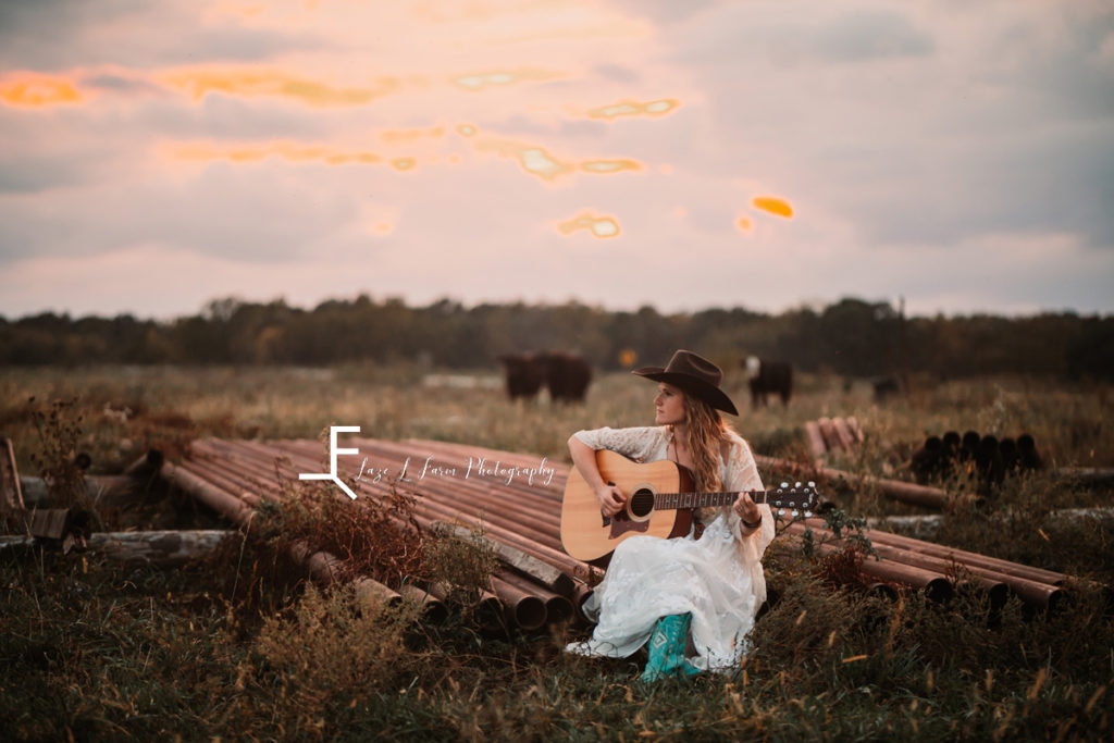 cowgirl in white dress playing guitar at sunset