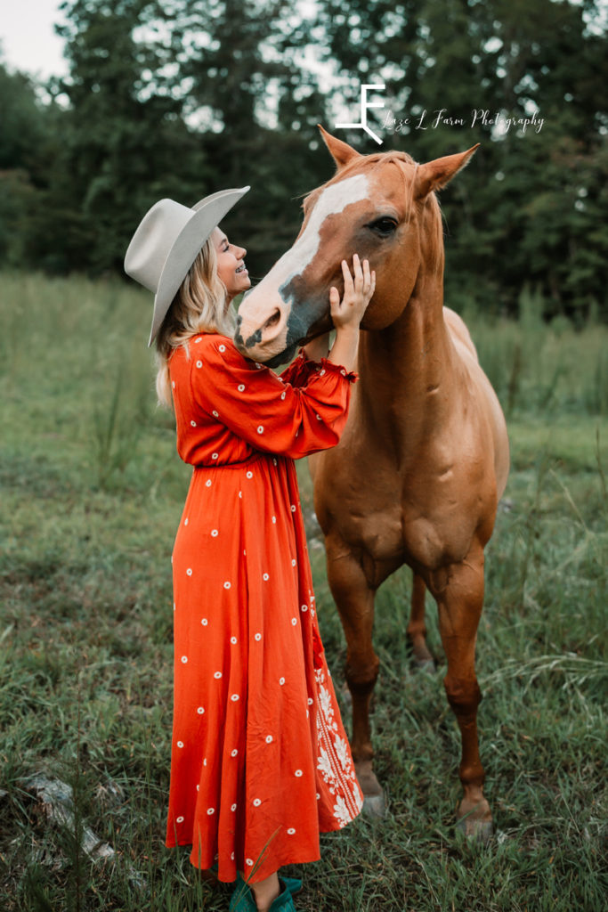 cowgirl in western dress hugging horse