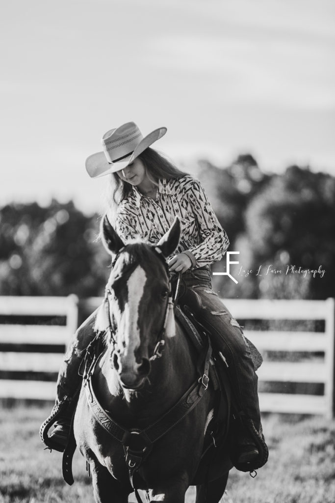 cowgirl riding looking at her horse in black and white