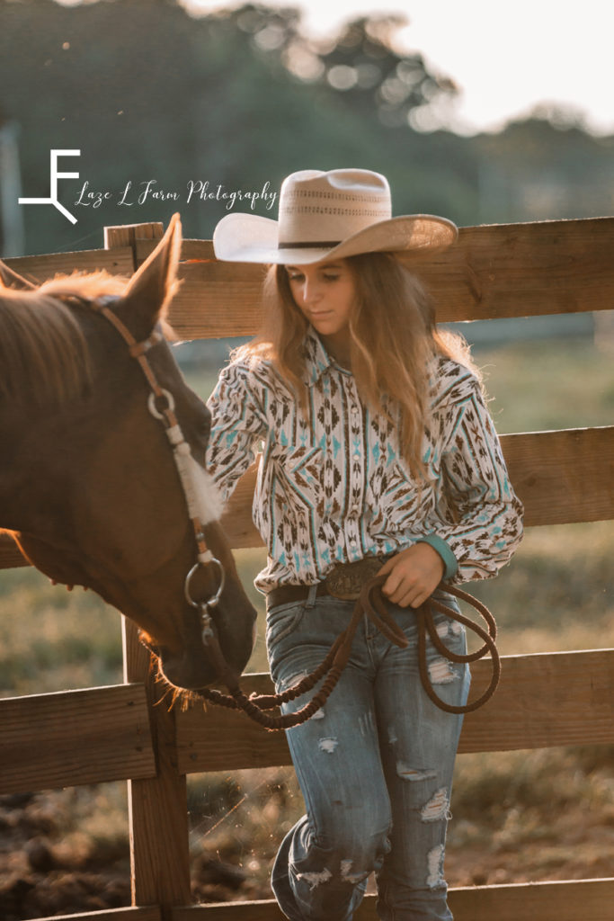 cowgirl petting her horse leaning on fence