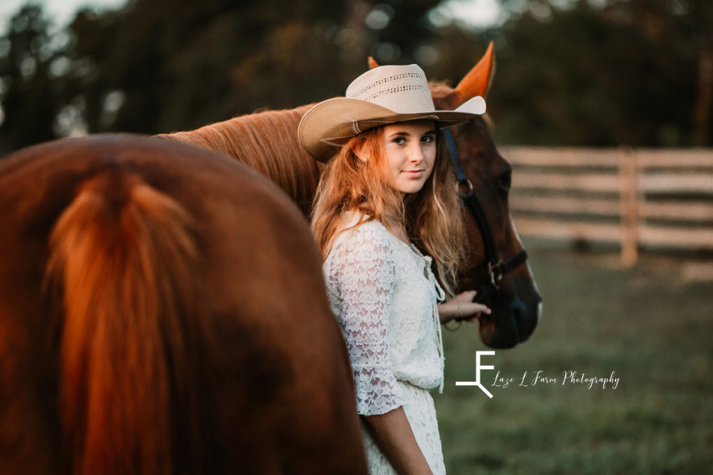 cowgirl in white dress with horse looking back