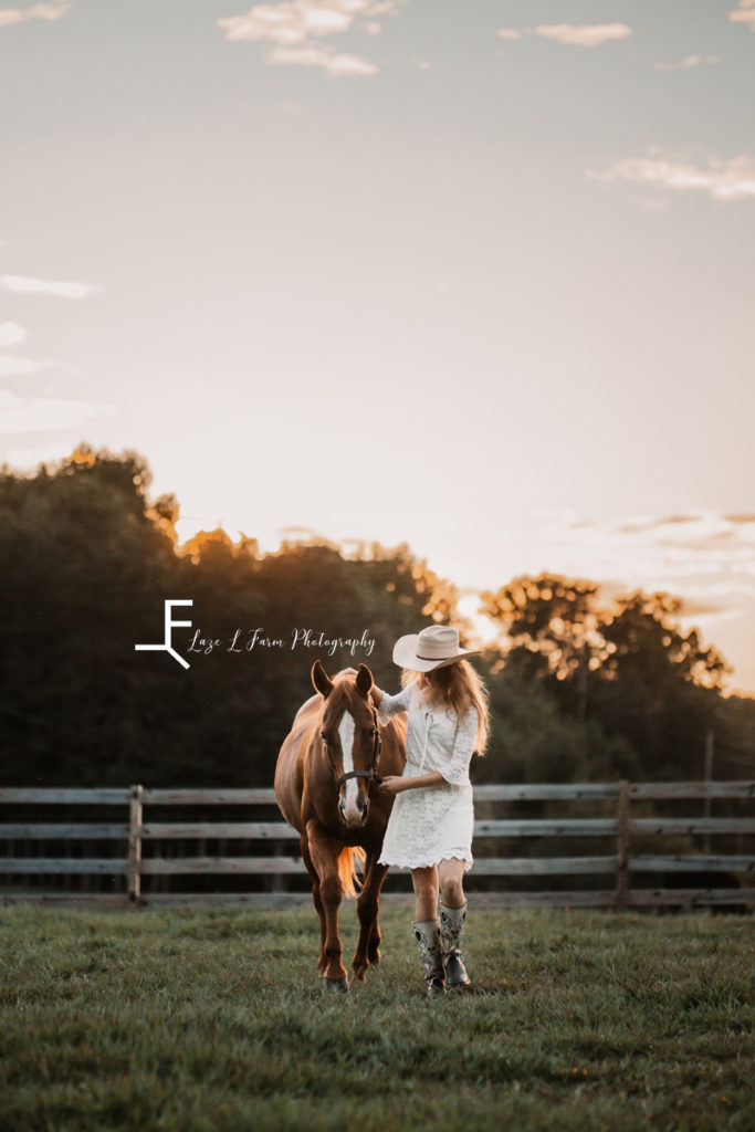 cowgirl in white dress walking with horse