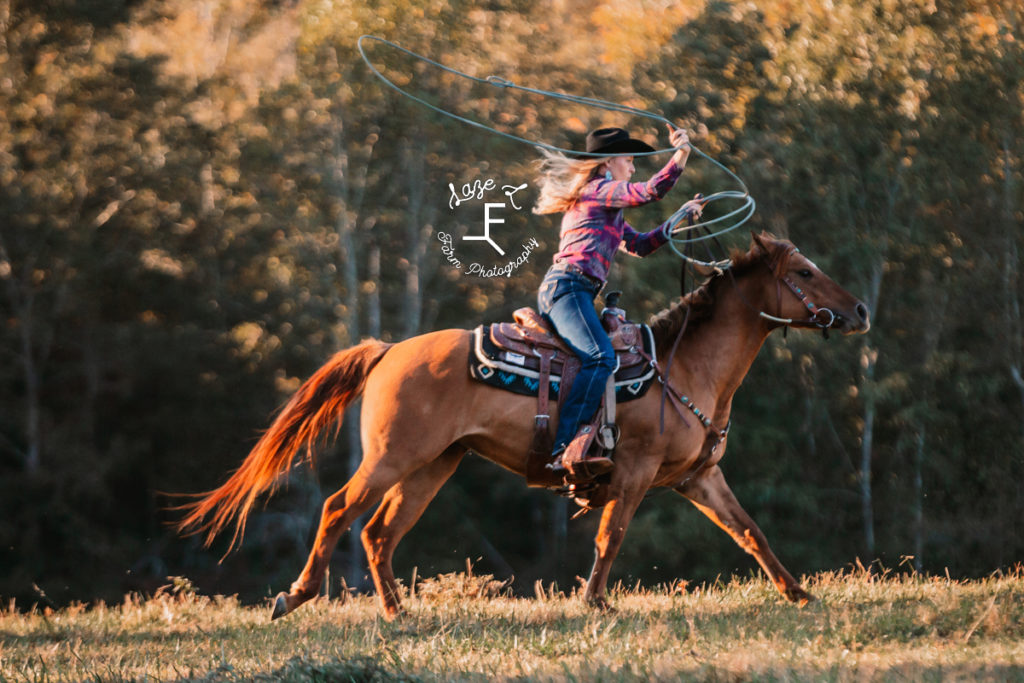 blonde cowgirl loping with rope swinging above head