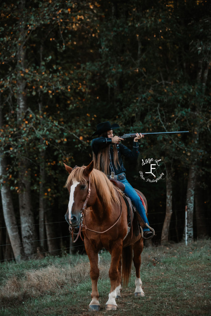 cowgirl aiming with long old gun on horseback