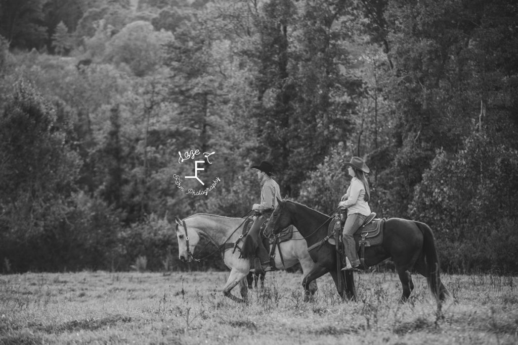 cowboy and cowgirl riding in black and white