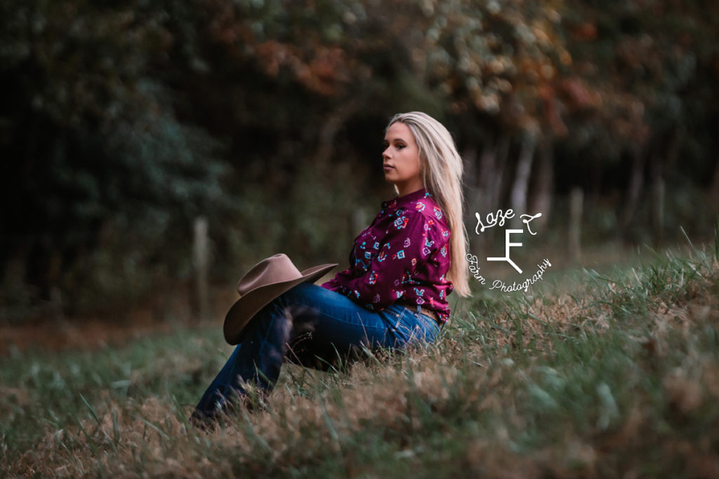 blonde cowgirl sitting in grass