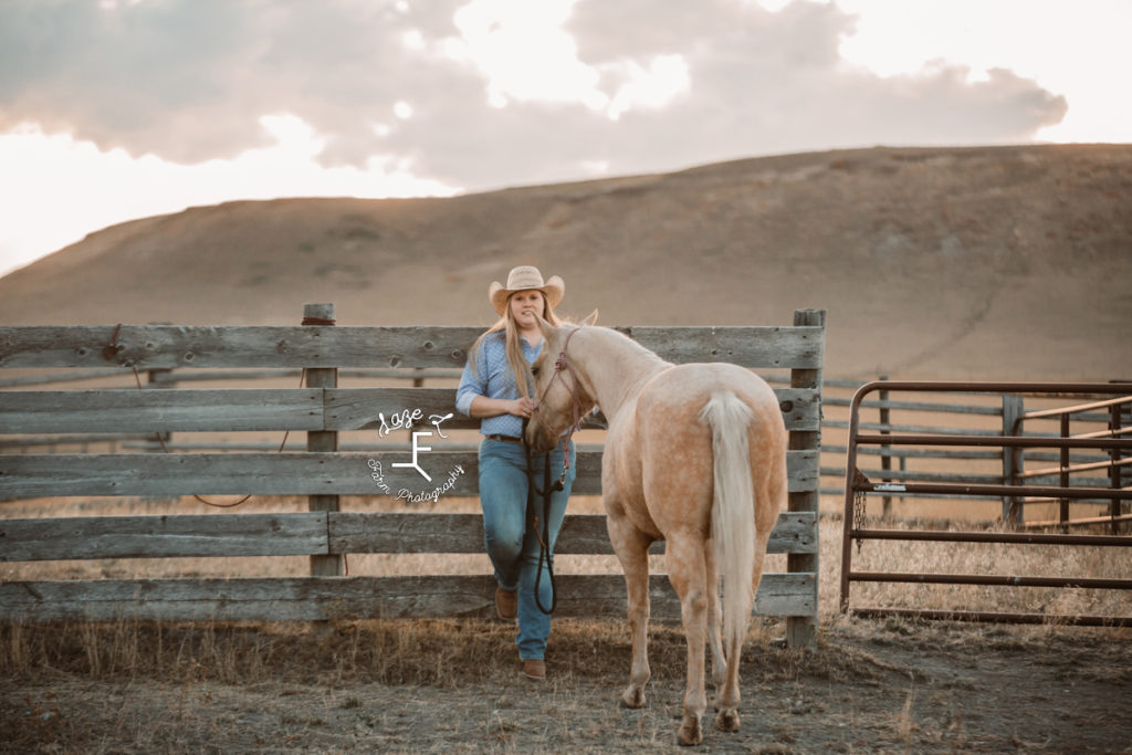 blonde cowgirl with palomino against fence