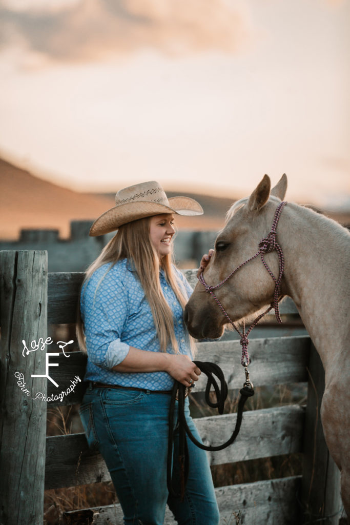 blonde cowgirl with her horse against fence