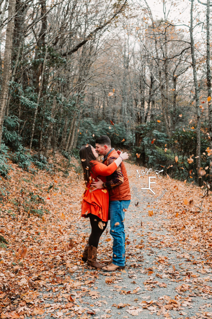 couple kissing under falling leaves