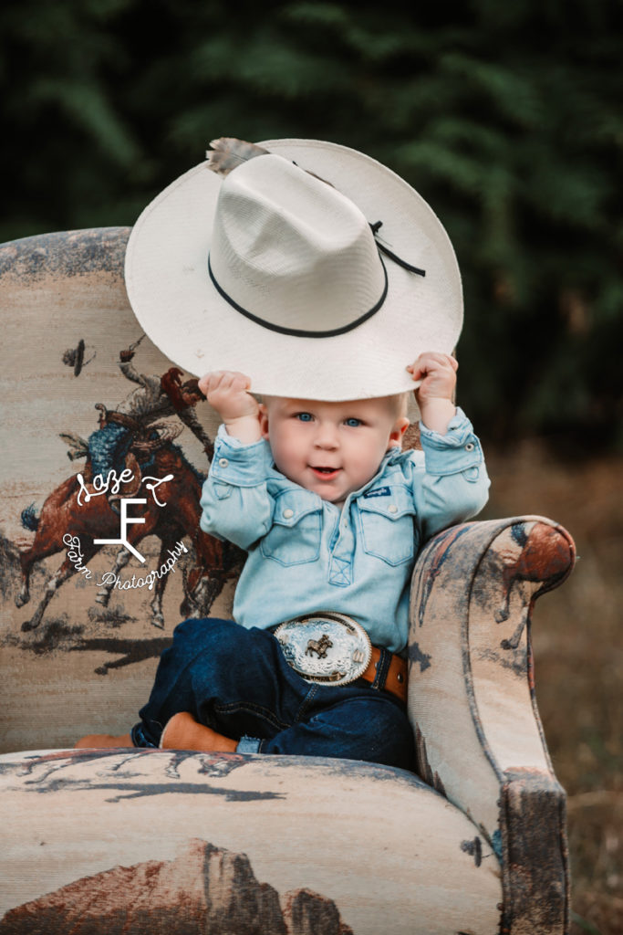 little cowboy holding hat smiling