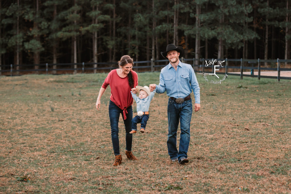 mom little cowboy and dad walking swinging little one