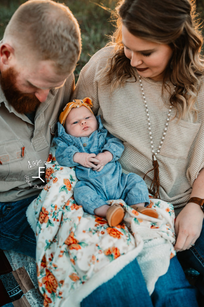 mom and dad holding baby girl looking at her