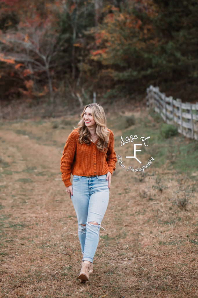 senior girl walking in orange sweater