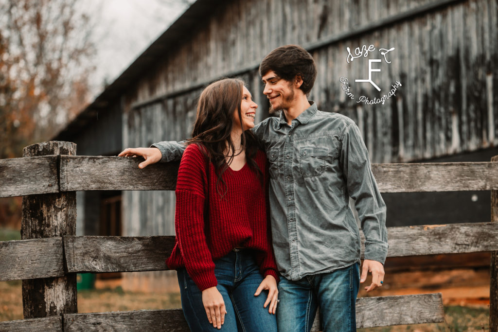 couple in front of barn looking at each other