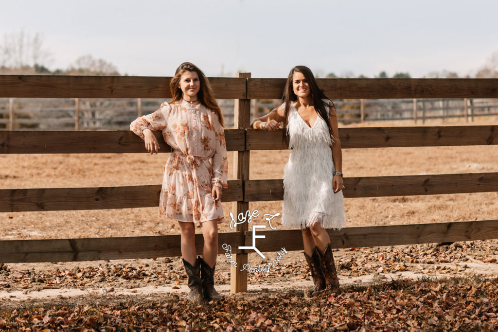 2 ladies standing against a fence
