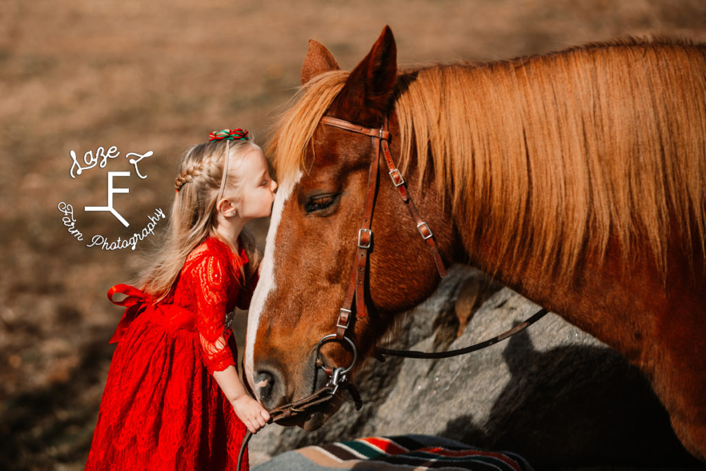 blond hair little girl giving horse a kiss