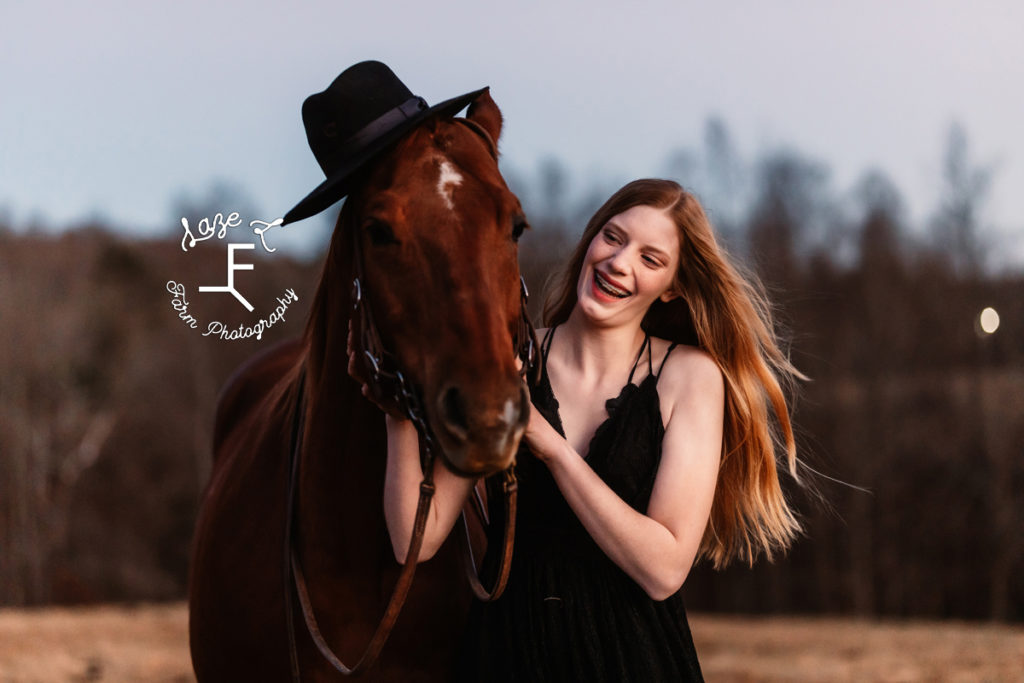 girl wearing black dress with horse wearing her hat