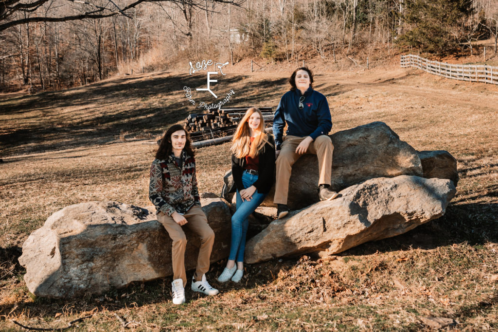 2 brothers and sister sitting on rock