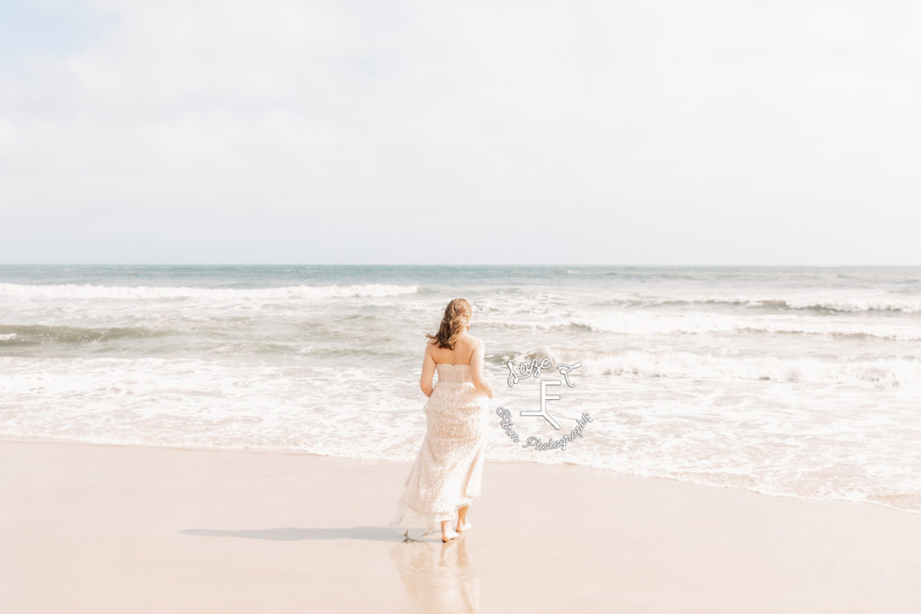 girl in beige dress walking to the ocean