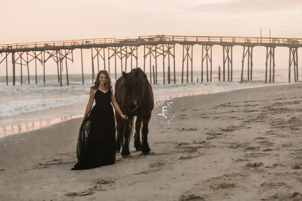 girl in black dress on beach at sunset with horse